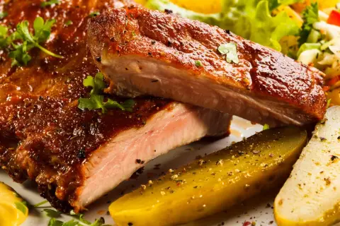 Succulente costine al forno, glassate e cotte alla perfezione, servite con cetriolini e insalata fresca.