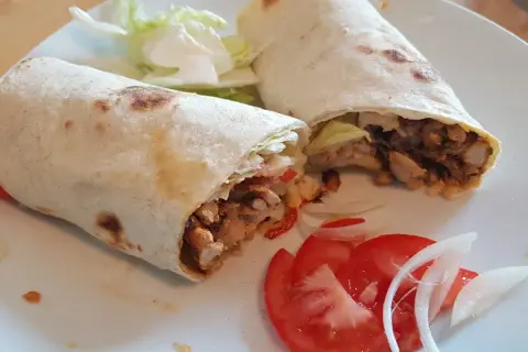 Due deliziosi kebab fatti in casa, ripieni di carne saporita, verdure fresche e serviti con pomodoro e cipolla.