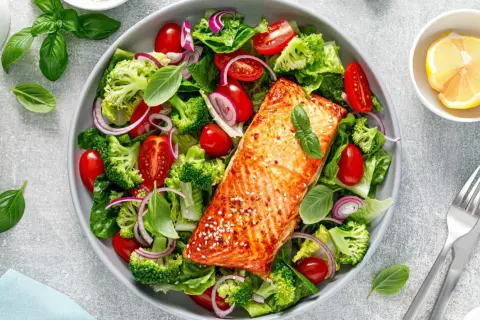 Insalata colorata con salmone alla griglia, broccoli, pomodorini e cipolla rossa. Un piatto gustoso e leggero, ideale per chi cerca cibi senza carboidrati.