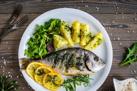 Orata in padella, cotta alla perfezione, servita con patate, limone e insalata fresca. Un piatto delizioso e salutare.