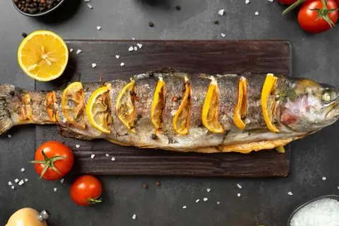 Trota al forno con fette di limone, pomodorini e sale grosso. Un piatto che ricorda i sapori del mare, ma che non appartiene ai crostacei quali sono.