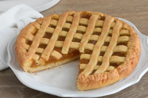 Una deliziosa crostata di marmellata, con la sua tipica griglia dorata, pronta per essere gustata.
