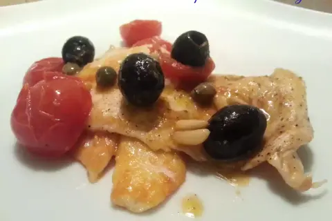 Petto di pollo cotto con pomodorini, olive nere, capperi e pinoli. Un modo diverso per preparare il petto di pollo.