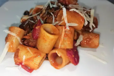 Mezze maniche alla norma con melanzane fritte, pomodoro e ricotta salata grattugiata. Un piatto siciliano gustoso.
