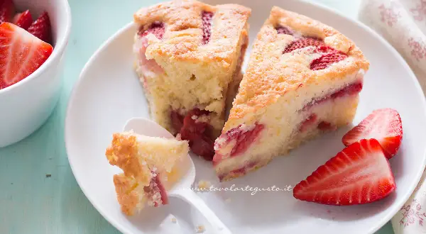 Fette di torta di fragole soffice e profumata, con fragole fresche e una cucchiaiata appena assaggiata.