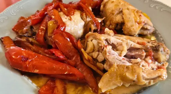 Piatto di pollo alla romana con peperoni rossi arrostiti, succulento e saporito.