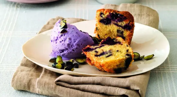 Frumina, cosa è? Un delizioso dolce con mirtilli e gelato viola, guarnito con frutta fresca.