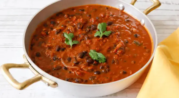 Un invitante piatto di fagioli alla messicana, con fagioli neri in una salsa rossa speziata, guarnito con coriandolo fresco.