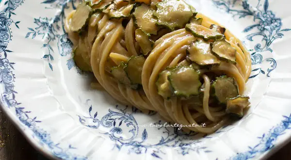Spaghetti alla Nerano, un piatto cremoso con zucchine fresche, servito su un piatto decorato con motivi blu.
