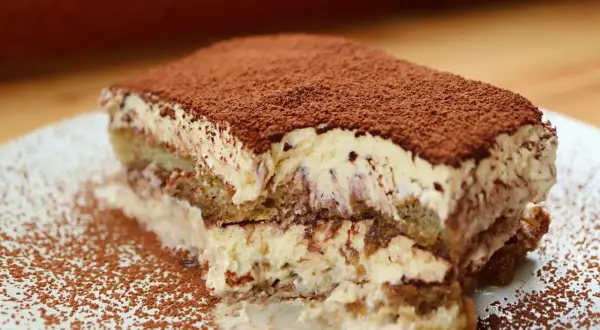 Una fetta di tiramisù, soffice e cremosa, cosparsa di cacao. Perfetta per un momento di dolcezza, anche in gravidanza.