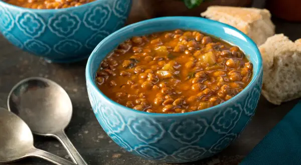 Due ciotole blu con un saporito stufato di riso e ceci, accompagnato da pane rustico e verdure fresche.