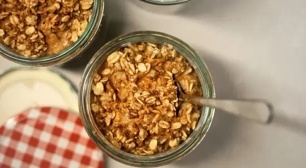 Un cucchiaino affonda in un vasetto pieno di fiocchi d'avena e cannella, pronti per essere gustati. Ecco come mangiare i fiocchi d'avena per una colazione sana.