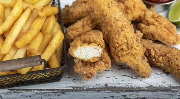 Straccetti di pollo impanati croccanti e patatine fritte dorate, un classico per un pasto gustoso.