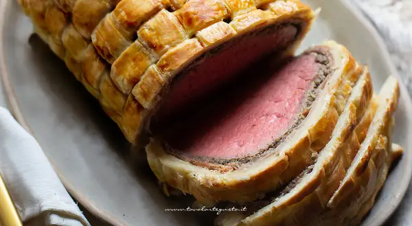 Un succulento filetto alla Wellington, cotto alla perfezione e avvolto in pasta sfoglia dorata, pronto per essere gustato.