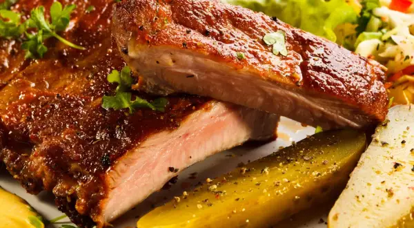 Succulente costine al forno, glassate e cotte alla perfezione, servite con cetriolini e insalata fresca.