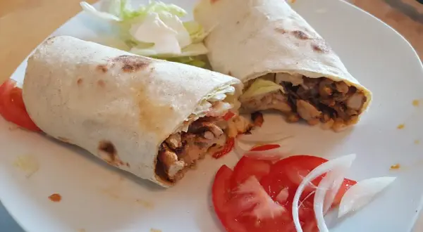 Due deliziosi kebab fatti in casa, ripieni di carne saporita, verdure fresche e serviti con pomodoro e cipolla.