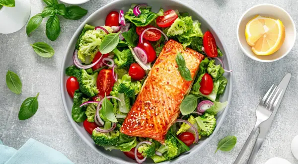 Insalata colorata con salmone alla griglia, broccoli, pomodorini e cipolla rossa. Un piatto gustoso e leggero, ideale per chi cerca cibi senza carboidrati.