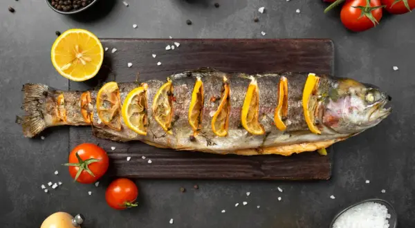 Trota al forno con fette di limone, pomodorini e sale grosso. Un piatto che ricorda i sapori del mare, ma che non appartiene ai crostacei quali sono.