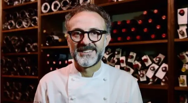 Un sorriso tra gli scaffali di bottiglie di vino, un ritratto di uno dei tanti chef stellati italiani che rendono la cucina italiana famosa nel mondo.