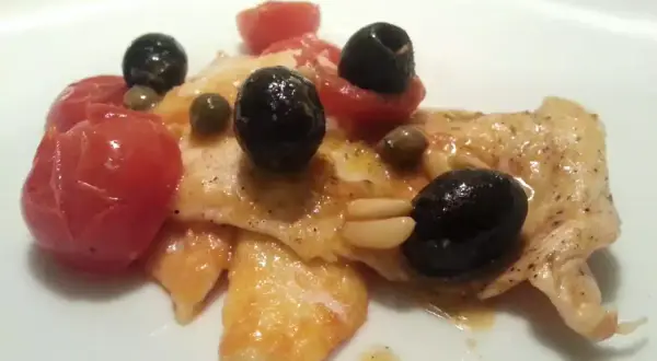 Petto di pollo cotto con pomodorini, olive nere, capperi e pinoli. Un modo diverso per preparare il petto di pollo.