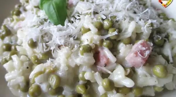 Un cremoso riso con piselli, guarnito con parmigiano grattugiato e un rametto di basilico. Un piatto che sa di casa.