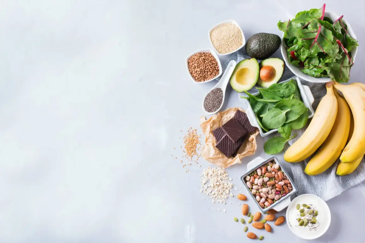 Banane, spinaci, avocado, cioccolato fondente e altri 20 alimenti che alzano la pressione, disposti su un piano grigio.