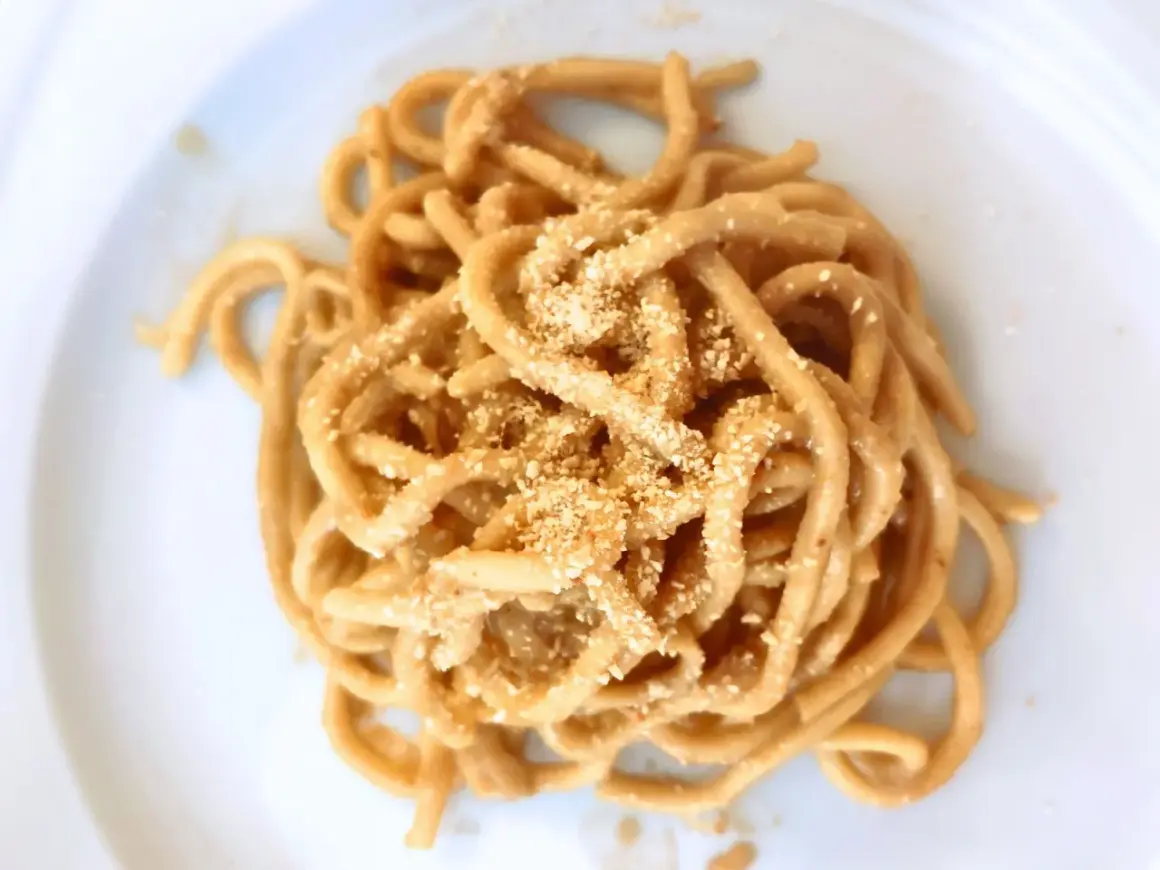Un piatto di bigoli in salsa, pasta spessa condita con un sugo saporito e cosparsa di pangrattato tostato.