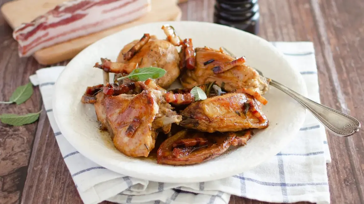 Delizioso coniglio in padella, dorato e succulento, guarnito con pancetta croccante e foglie di salvia fresca.