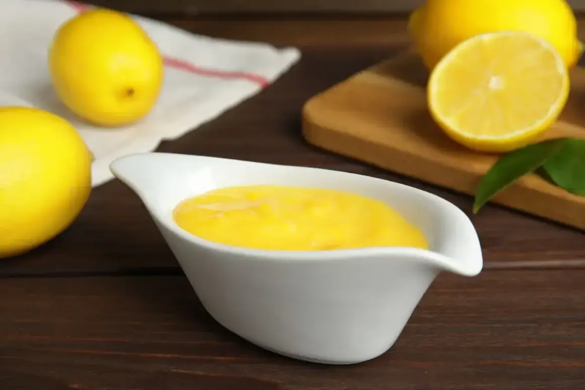 Una ciotola bianca contiene una deliziosa crema al limone, con limoni freschi sullo sfondo.