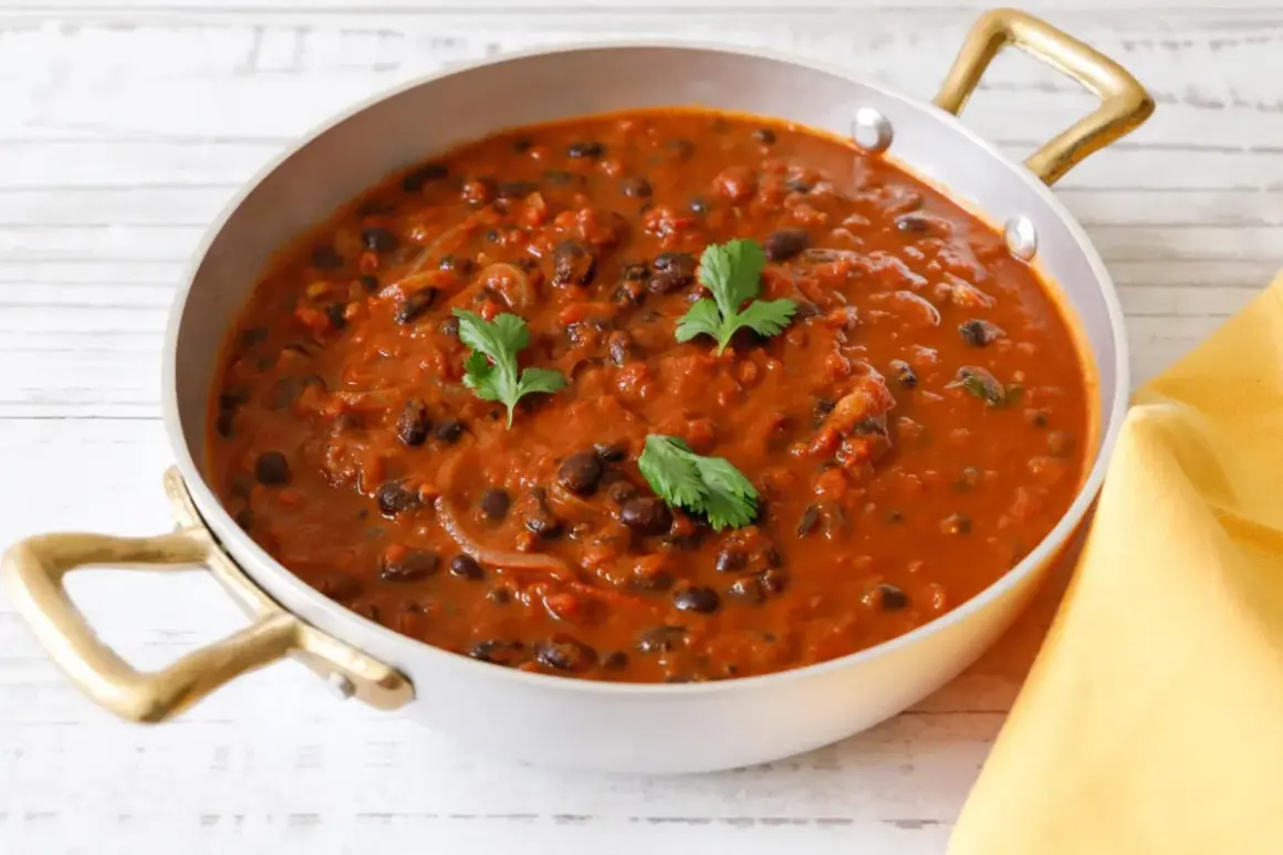 Un invitante piatto di fagioli alla messicana, con fagioli neri in una salsa rossa speziata, guarnito con coriandolo fresco.