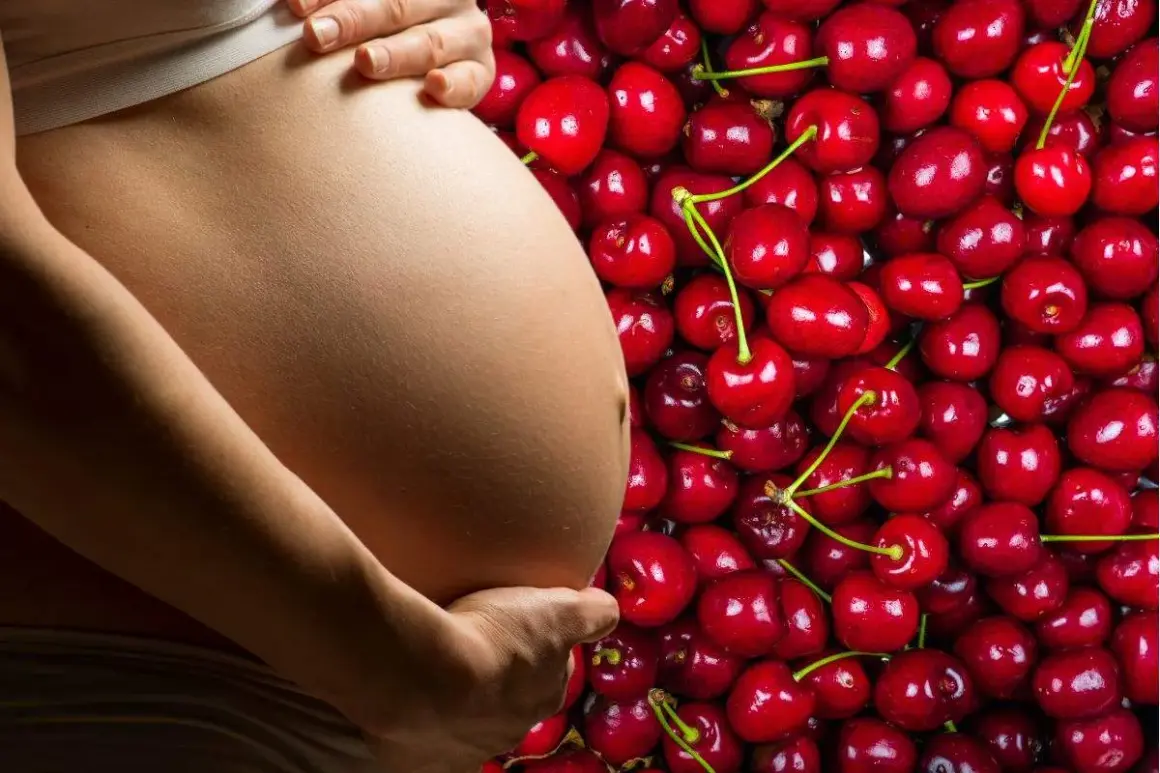 Pancia di donna incinta accarezzata, circondata da un mare di ciliegie rosse, simbolo di dolce attesa e ciliegie in gravidanza.