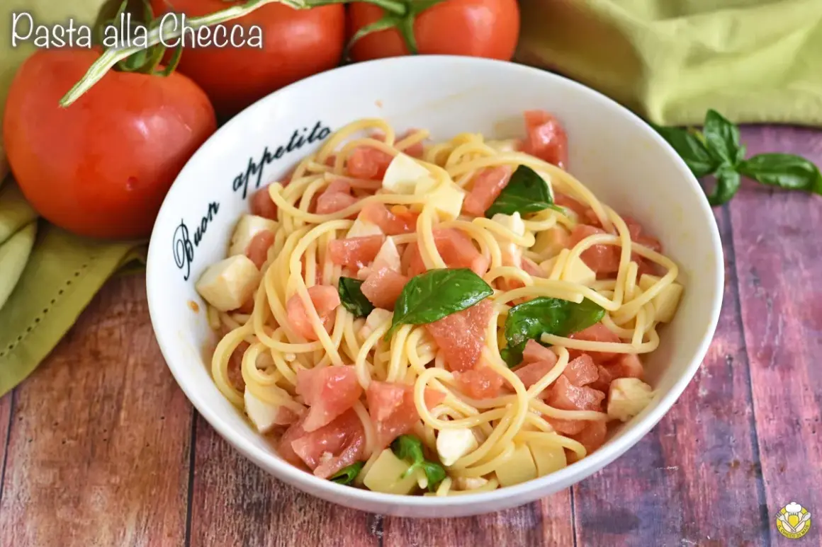 Un piatto di pasta alla checca con pomodori freschi, mozzarella e basilico, pronto per essere gustato.