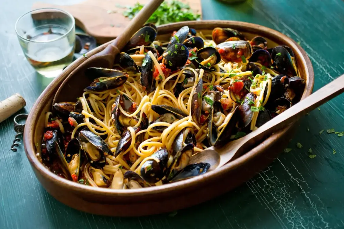 Un invitante piatto di spaghetti con le cozze, condito con pomodoro e prezzemolo, pronto per essere gustato.