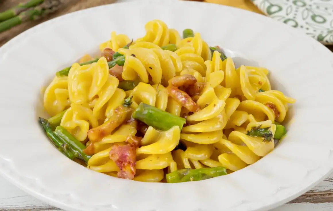 Fusilli cremosi con pancetta croccante e asparagi freschi, una deliziosa carbonara di asparagi.
