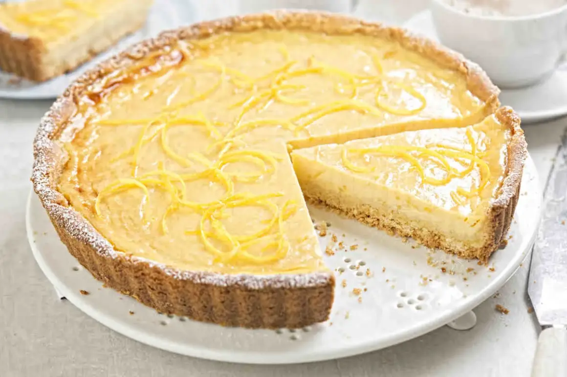 Una deliziosa crostata con crema pasticcera, guarnita con scorza di limone e spolverata di zucchero a velo. Perfetta per ogni occasione.