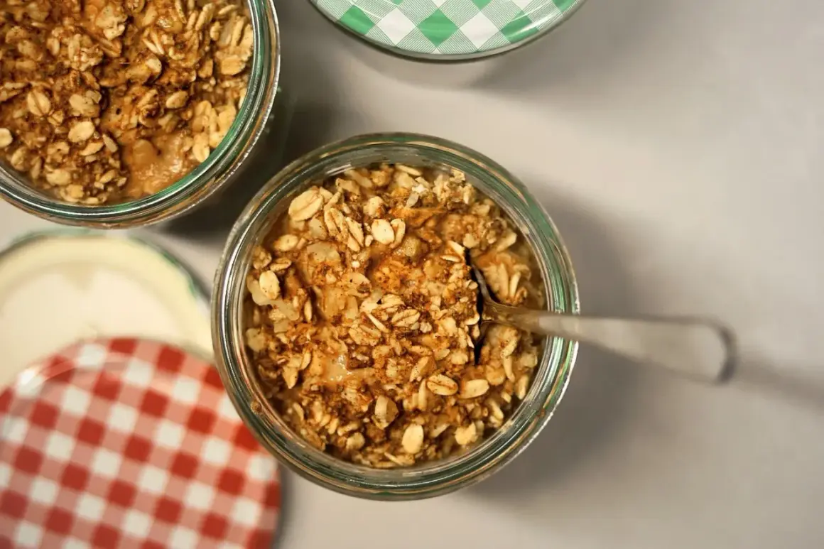 Un cucchiaino affonda in un vasetto pieno di fiocchi d'avena e cannella, pronti per essere gustati. Ecco come mangiare i fiocchi d'avena per una colazione sana.