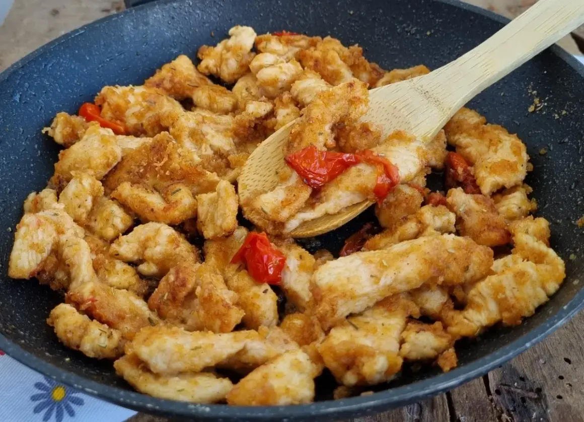 Straccetti di pollo dorati e saporiti in padella con pomodorini, pronti per essere gustati.