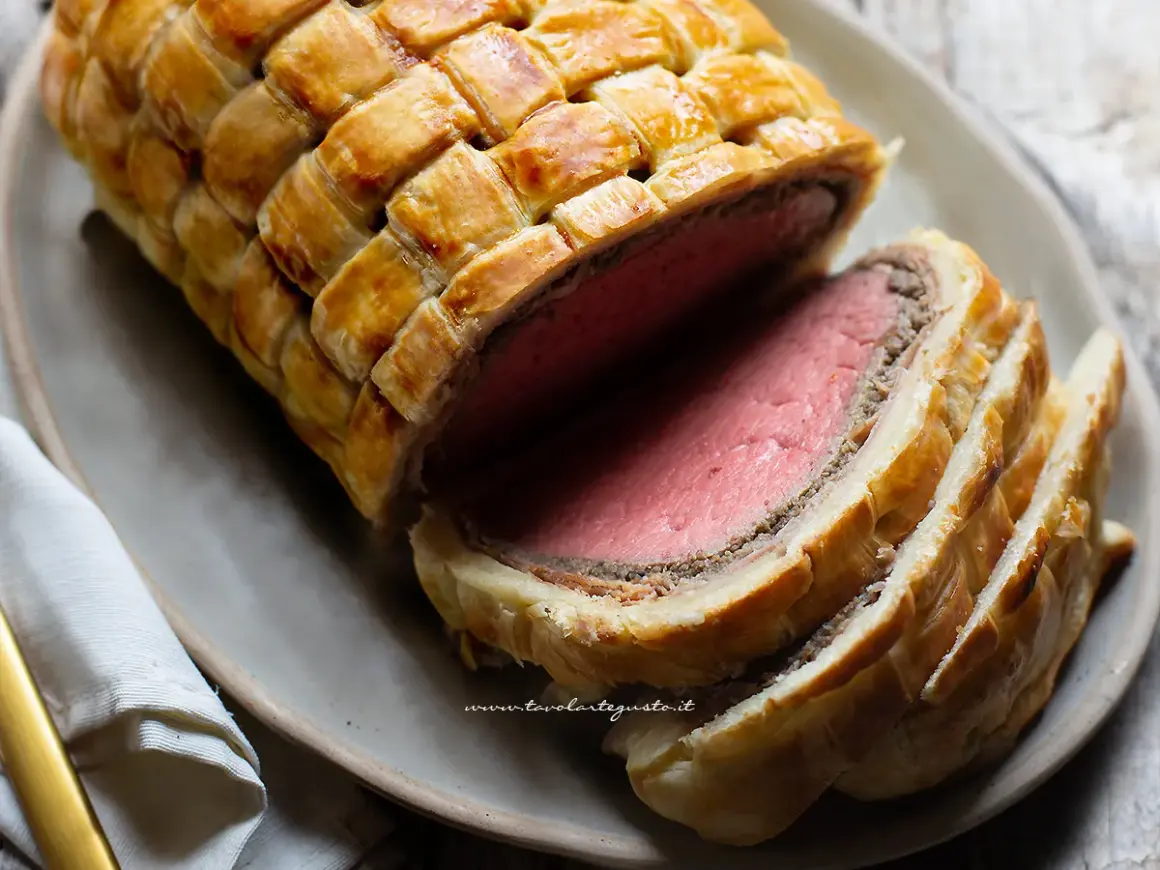 Un succulento filetto alla Wellington, cotto alla perfezione e avvolto in pasta sfoglia dorata, pronto per essere gustato.
