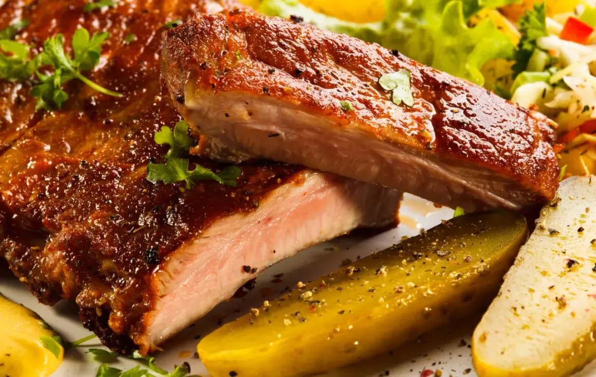 Succulente costine al forno, glassate e cotte alla perfezione, servite con cetriolini e insalata fresca.