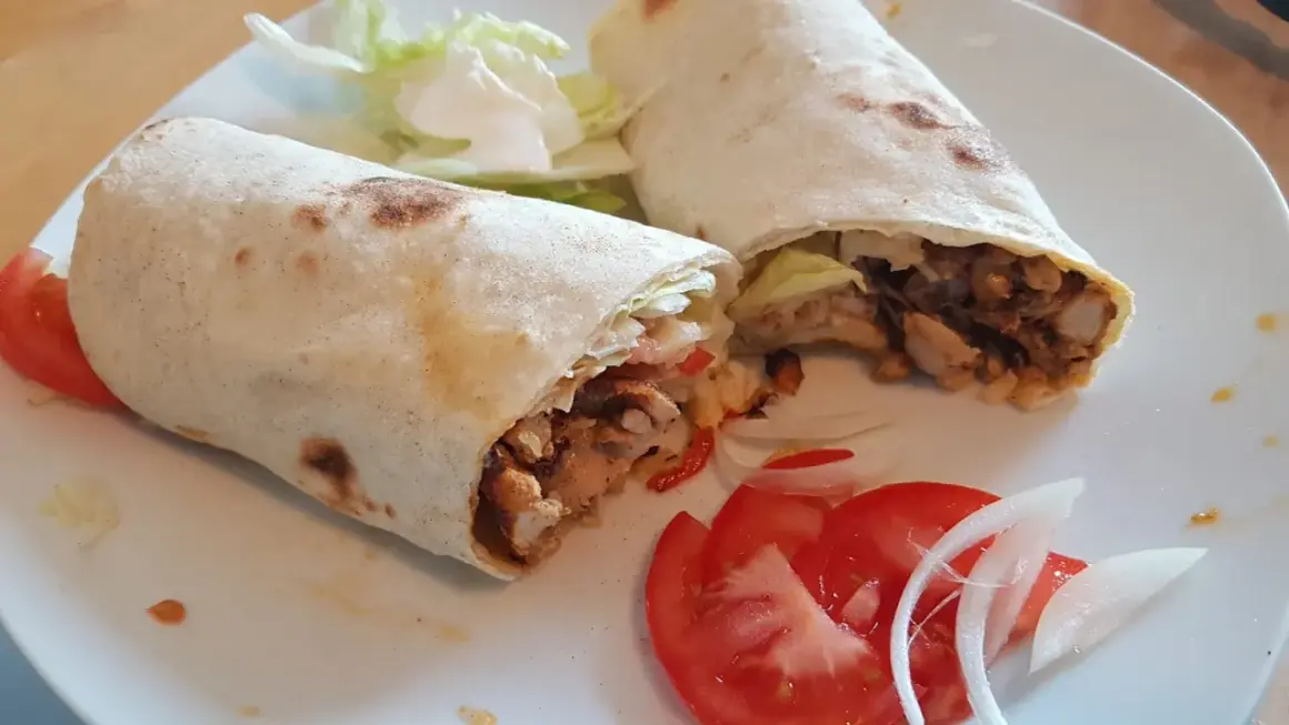 Due deliziosi kebab fatti in casa, ripieni di carne saporita, verdure fresche e serviti con pomodoro e cipolla.