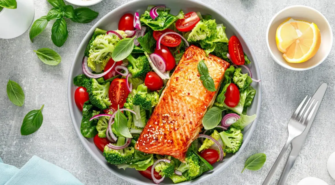 Insalata colorata con salmone alla griglia, broccoli, pomodorini e cipolla rossa. Un piatto gustoso e leggero, ideale per chi cerca cibi senza carboidrati.