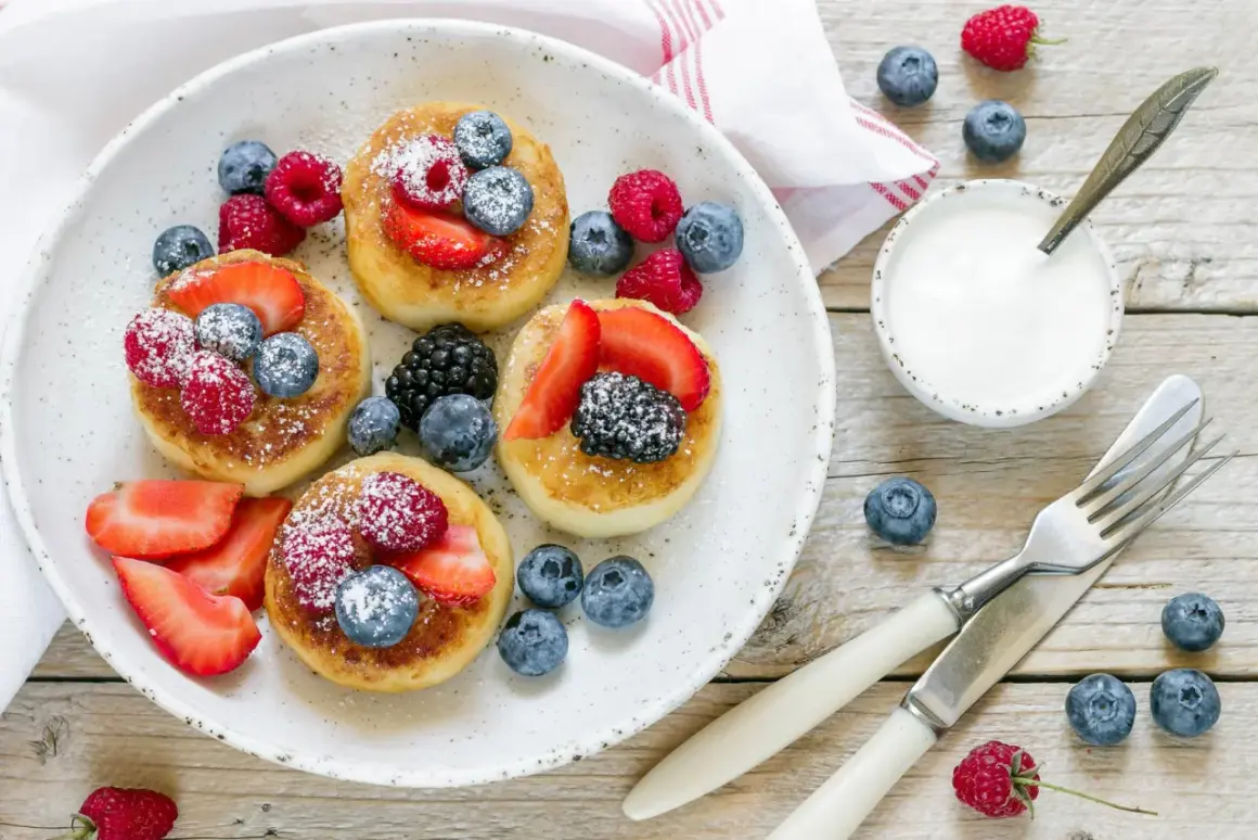 Deliziosi pancake senza glutine guarniti con fragole, lamponi, mirtilli e more. Serviti con yogurt e spolverata di zucchero a velo.