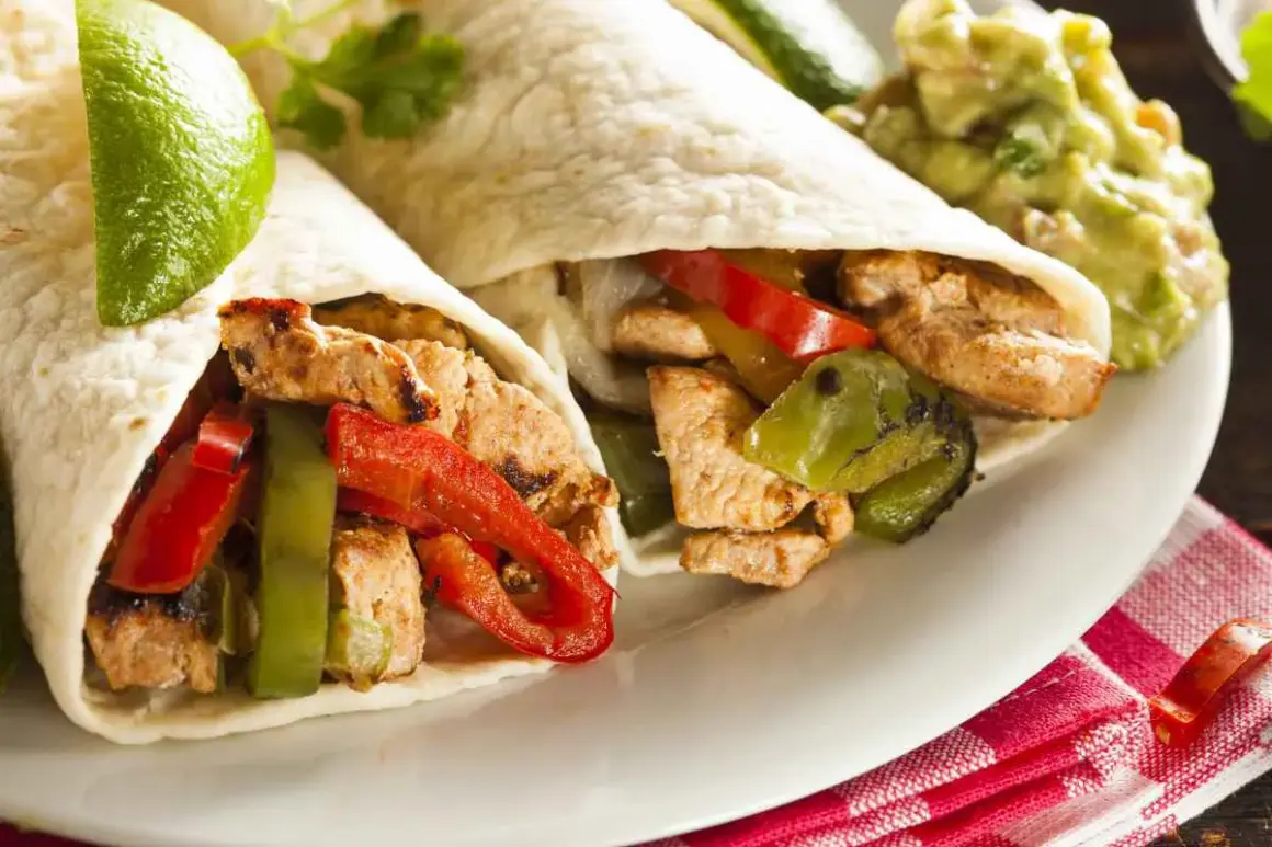 Due fajitas di pollo con peperoni, cipolle e guacamole. Un piatto saporito e colorato, pronto per essere gustato.