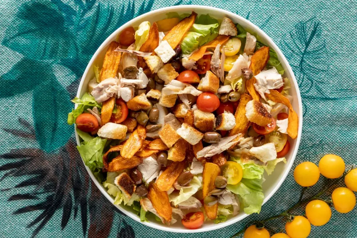 Insalata di pollo ricca con crostini, pomodorini, olive e patate dolci croccanti. Un piatto gustoso e colorato.