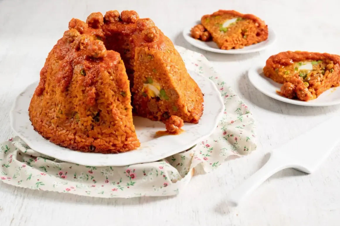Sartu di riso, un tortino di riso rosso con polpettine e uova sode, servito su un piatto con tovagliolo fiorato.