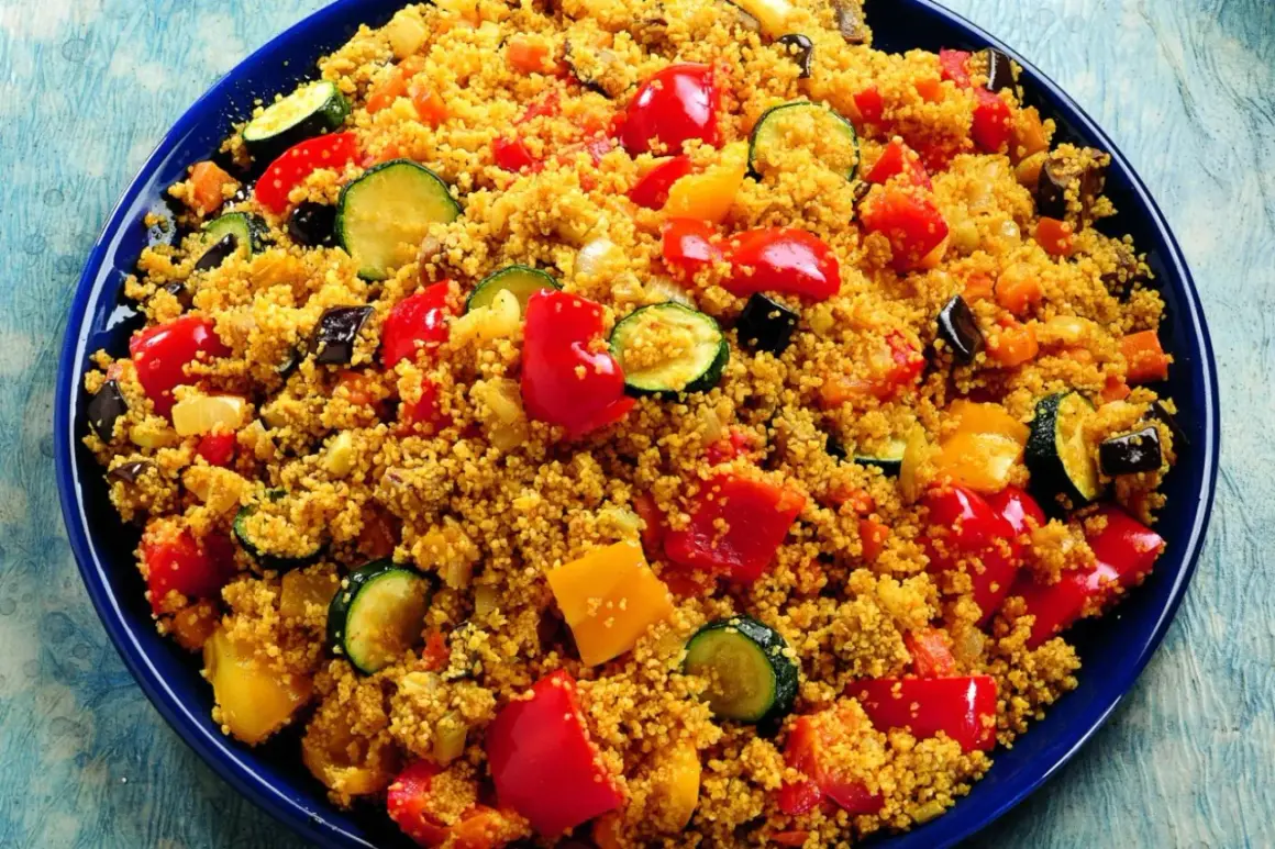 Un piatto colorato di cous cous con verdure miste: peperoni rossi e gialli, zucchine e melanzane.