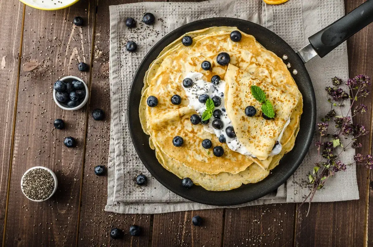 Deliziose crepes senza glutine con mirtilli e panna, un piacere per gli occhi e per il palato.