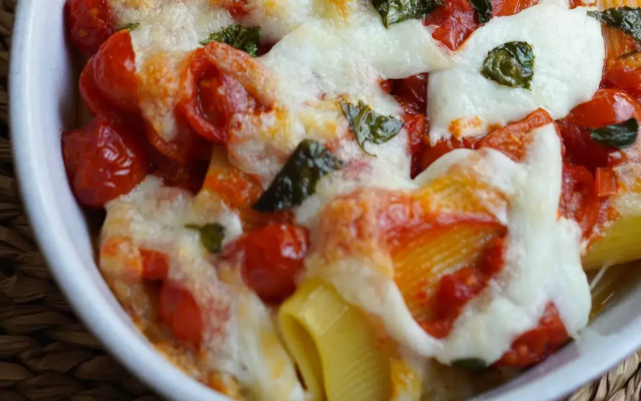Un primo piatto invitante: pasta alla sorrentina con pomodorini succosi, mozzarella filante e basilico fresco, cotta al forno.