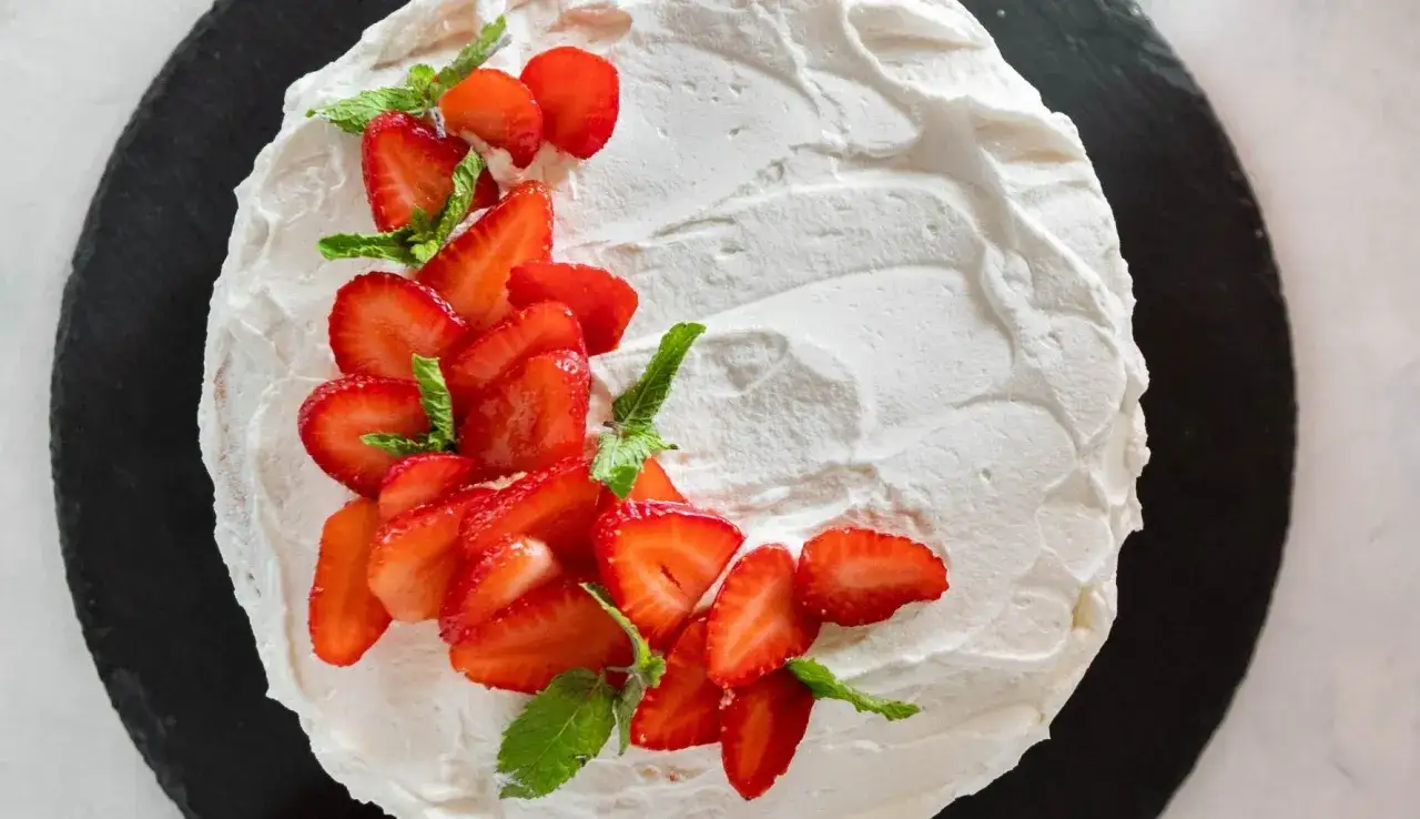 Deliziosa torta di fragole con panna montata e foglie di menta, un'esplosione di freschezza e dolcezza.
