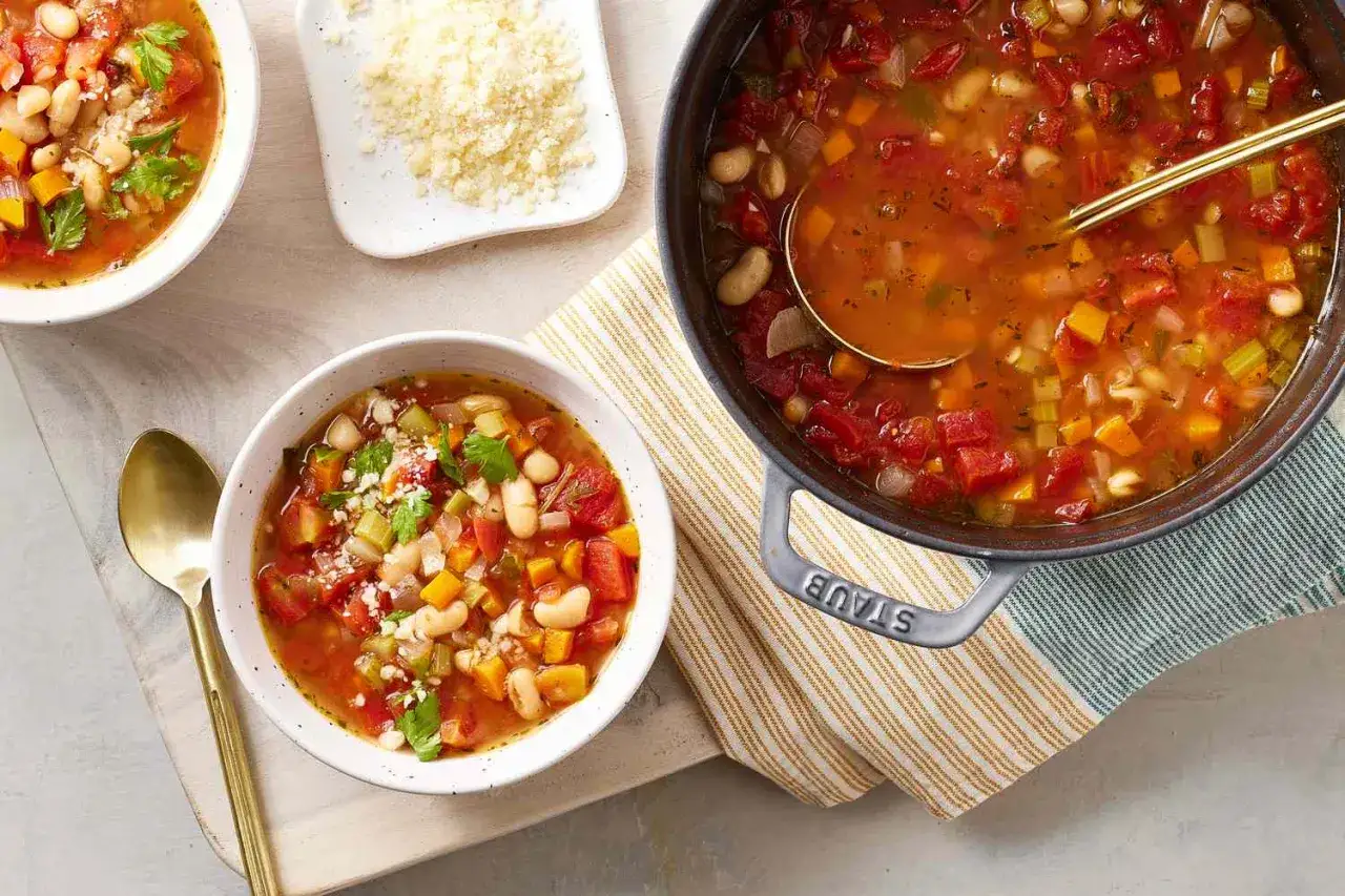 Minestrone fumante, perfetto per la dieta del minestrone, servito in ciotole con parmigiano grattugiato.